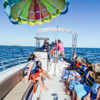 a group of people on a boat with two people about to go parasailing