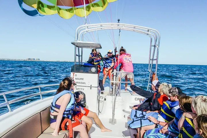 a group of people on a boat with two people about to go parasailing