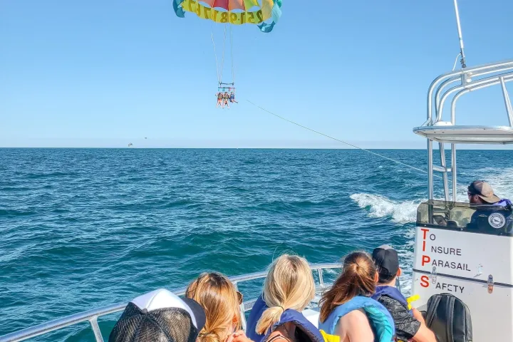 a group of people in a boat watching people parasail
