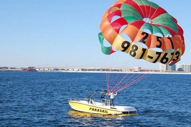 a small boat in a body of water with a parasailing parachute
